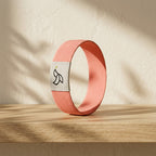 Coral-pink Daily Verse Bracelet standing on an oak shelf in warm morning light