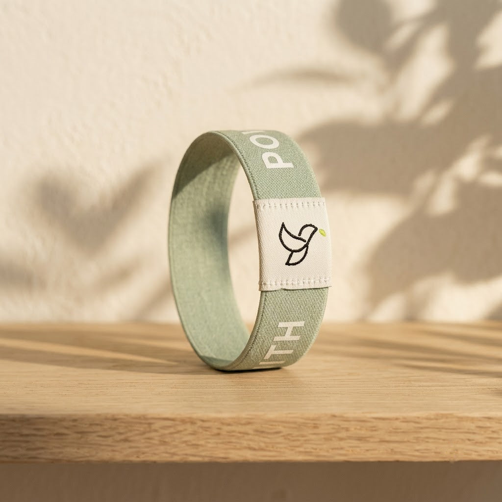 Sage Green Daily Verse Bracelet with dove tag on an oak shelf