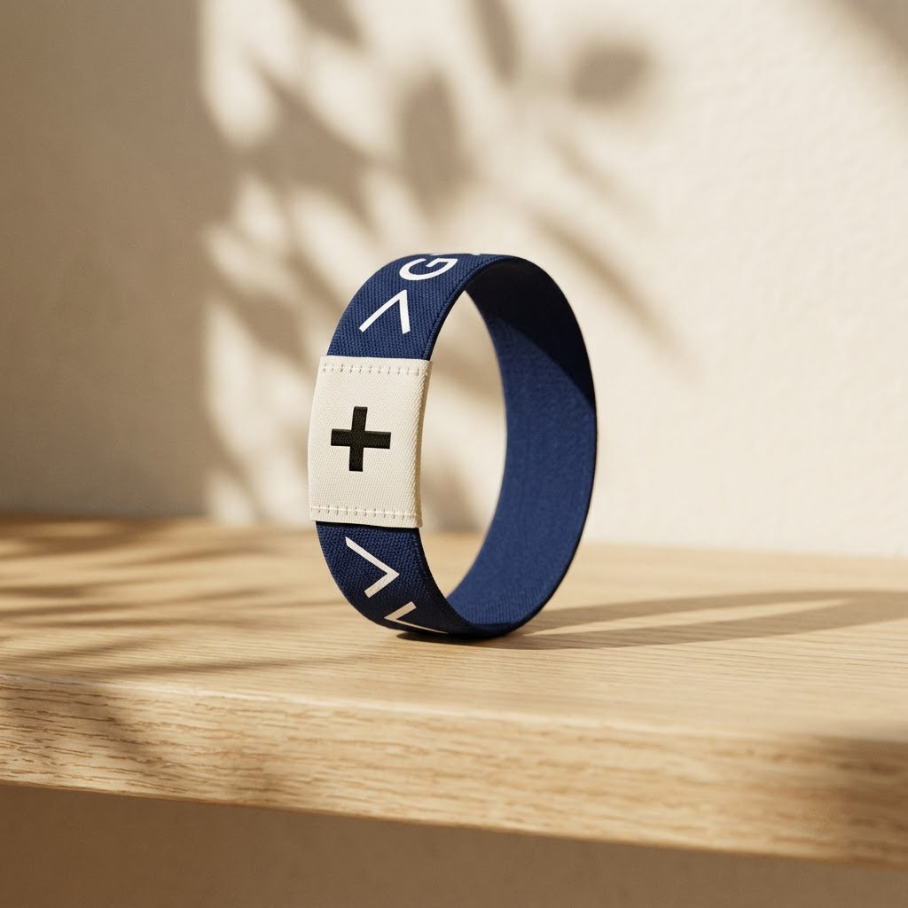 Navy Daily Verse Bracelet with cross tag on an oak shelf