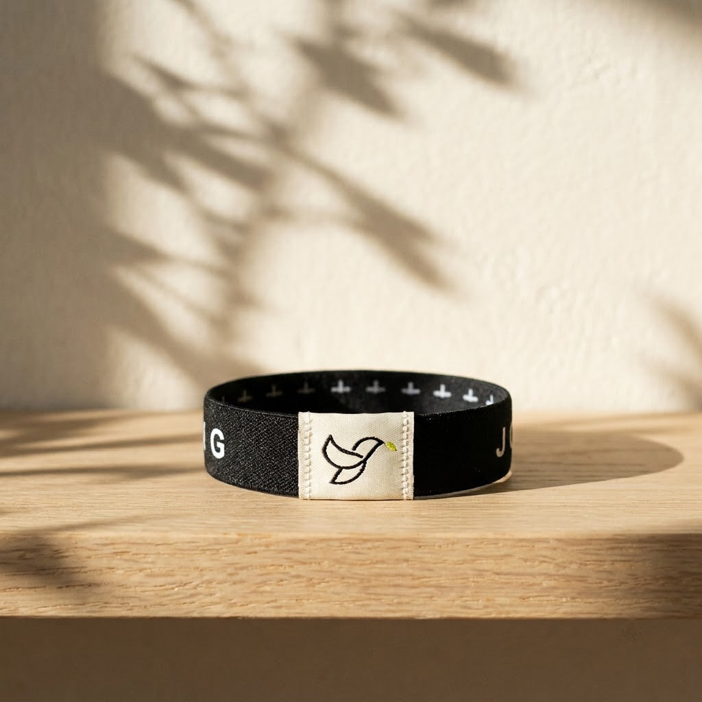 Black Daily Verse Bracelet with dove tag on an oak shelf