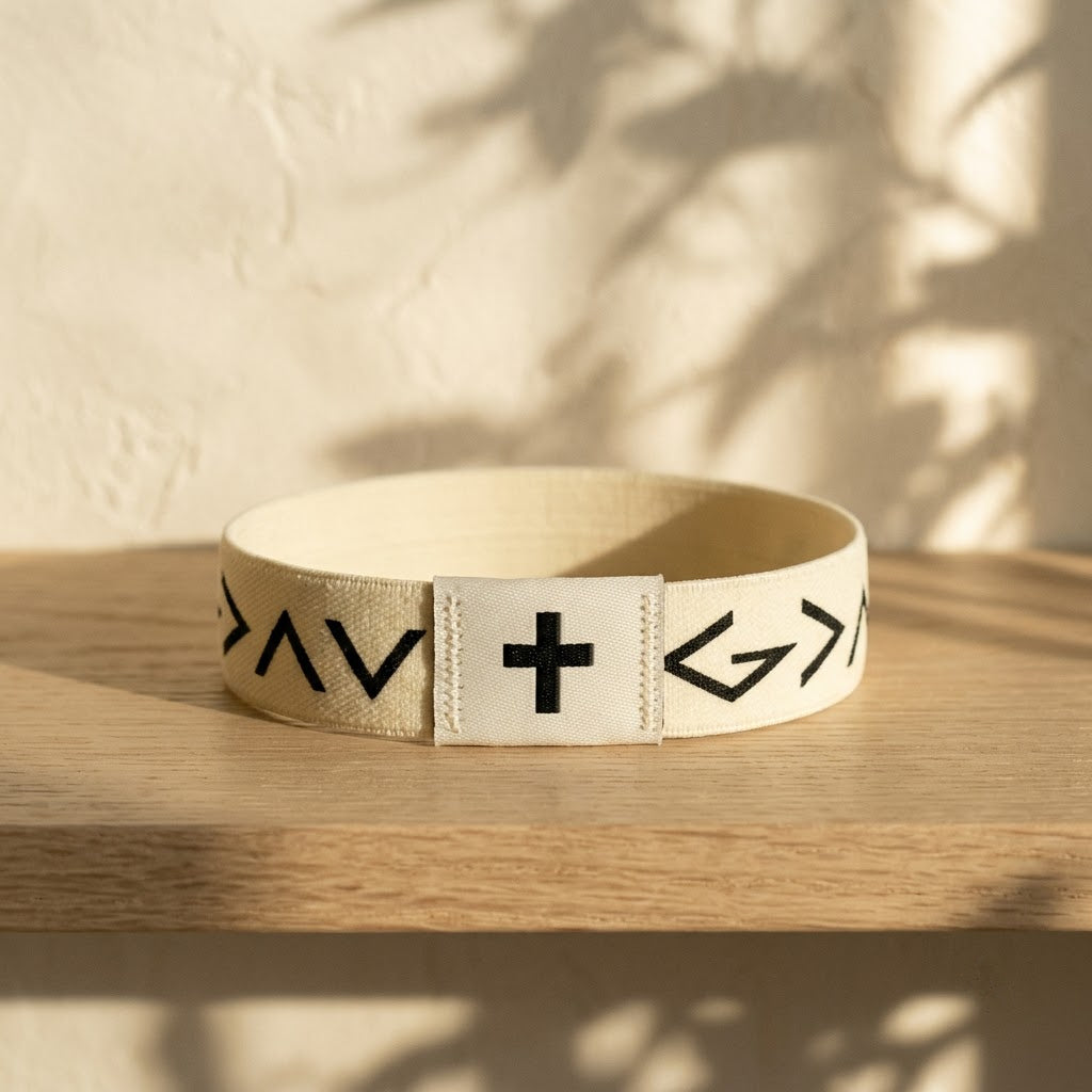 Cream Daily Verse Bracelet with cross tag on an oak shelf
