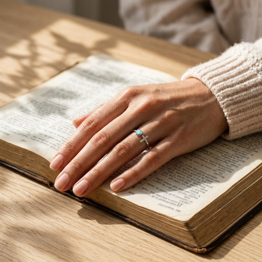Heart of Faith Opal Cross Ring, styled with an open Bible